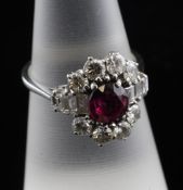 An 18ct white gold, ruby and diamond cluster ring, of oval form, the oval cut ruby weighing 1.