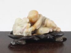 A Chinese soapstone group of a boy and two rabbits, 20th century, the boy crouching next to the