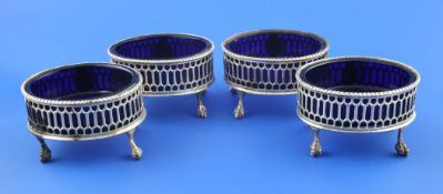 A set of four George III pierced silver oval salts, with gadrooned borders, blue glass liners, on