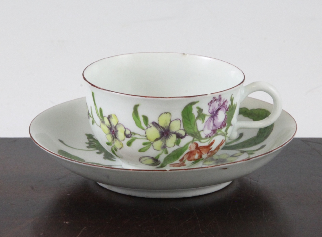 A Worcester polychrome cup and saucer, c.1760, painted throughout with flowers and fruit, probably