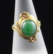 A gold and cabochon jadeite ring, with semi-translucent stone in a collet setting, with foliate