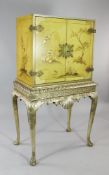 A late 17th century style yellow painted and silvered cabinet on stand, decorated with typical