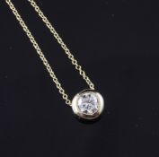 An 18ct gold and collet set solitaire diamond pendant necklace, the round cut stone weighing