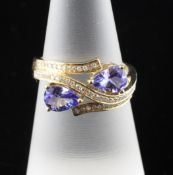 A 14ct gold, diamond and pear shaped tanzanite set crossover ring, size M.