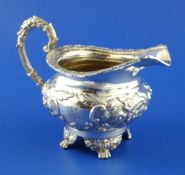 A Victorian silver cream jug, of squat circular form, with engraved monogram, ornate handle and