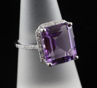 A 14ct white gold, amethyst and diamond ring, set with emerald cut amethyst and diamond set border