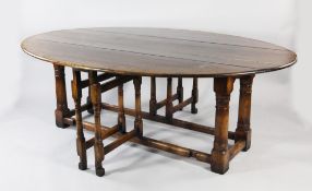 An 18th century oval oak wake table, with drop leaves and turned gun barrel supports, extends to 7ft