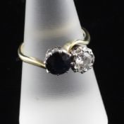An 18ct gold, two stone diamond and sapphire crossover ring, with illusion set diamond, size O.