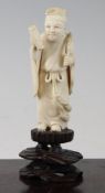 A Chinese ivory figure an immortal, early 20th century, holding a scroll and a fly wisk, on a carved