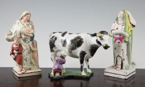 A Staffordshire pearlware cow creamer and two figures of Hope and Charity, c.1820, the standing