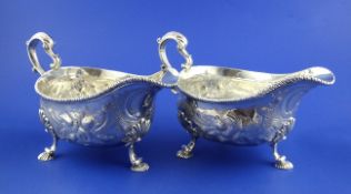 A handsome pair of late George II silver sauceboats, later embossed and engraved with scrolling