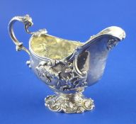 An ornate George III cast silver pedestal sauceboat, with engraved armorial and decorated with