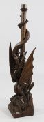 A late Victorian carved oak lamp base, modelled as an entwined dragon on a rocky base, carved with