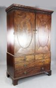 An early 19th century mahogany linen press, with oval panelled cupboard doors over two short and