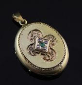 An ornate Victorian gold oval locket set with emerald and seed pearls, with pierced scroll gem set