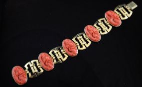 A Chinese 18ct gold and coral bracelet, set with five oval coral panels carved with dragons, 7.