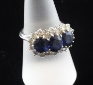 An 18ct white gold, sapphire and diamond cluster ring, the three oval cut sapphires within a
