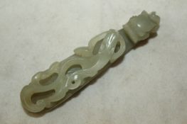 A Chinese celadon green jade belt hook, 19th century, carved in relief with a chi-dragon with a