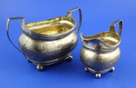 A George III silver sugar bowl and cream jug, of oval form, with engraved foliate bands and