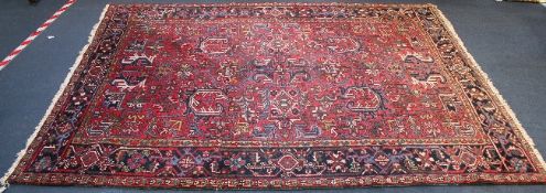 A Heriz carpet, with filed of geometric foliate motifs, on a red ground, with three row border, 9ft