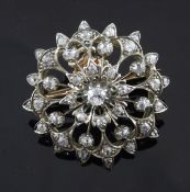 A gold and diamond set flower head pendant brooch, with pierced and engraved setting, set with old