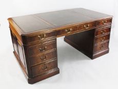 A George III style mahogany pedestal desk, with gilt tooled green leather skiver above an