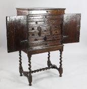 A 17th century style oak chest on stand, with hinged top above two cupboard doors enclosing an