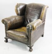 An early 20th century leather wingback armchair, with brass studs and carved mahogany show frame,