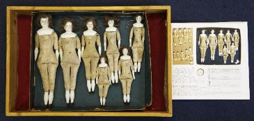 An early 20th century Hertwig & Co sample box of seven graduated Naking Puppen dolls, with mohair