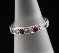 An 18ct white gold ruby and diamond full eternity ring, with carved shank and set with nine
