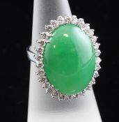A white gold, cabochon jadeite and diamond set ring, the oval stone bordered with brilliants, with
