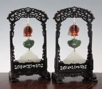 A pair of Chinese jade and chalcedony pendant plaques and wood stands, each suspended with twin