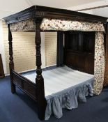 A 17th century style carved oak tester bed, with arched panels, lozenge carved decoration, baluster