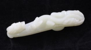 A Chinese white celadon jade belt hook, carved in relief with a chi-dragon, with dragon head