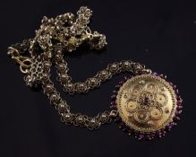 An Indian gold pendant with applied decoration and set with ruby cabochons, on fancy roundel link