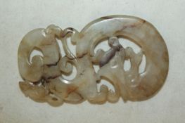 A Chinese white and russet jade plaque, Song dynasty or later, in the form of a scrolling sinuous