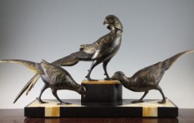 An Art Deco statuette group of three black and gold patinated metal pheasants, mounted on a yellow