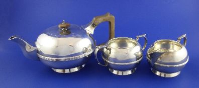 A 1930`s silver three piece tea set, of squat circular form, with reeded girdle, on spreading foot,