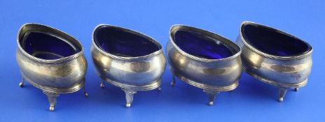A set of four George III silver boat shaped salts, with blue glass liners (3 replaced) and reeded