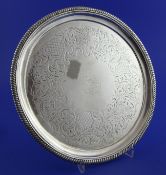 A George III silver circular salver, with engraved armorial and foliate scroll decoration, with