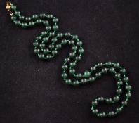A single strand dark ""imperial"" green jadeite bead necklace, with gilt metal spherical clasp,