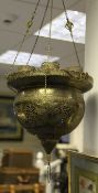 An Islamic pierced and engraved brass mosque lamp, with foliate scrolled panels and Arabic script,