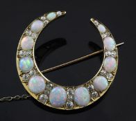 A 20th century gold, graduated white opal and diamond crescent brooch, set with eleven opals and