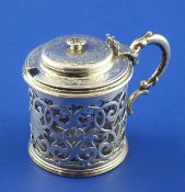 A Victorian pierced silver drum mustard and liner, with ornate scroll handle and floral engraved