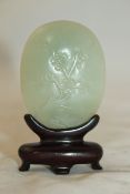 A Chinese celadon jade oval belt buckle, 19th century, carved in low relief with a prunus tree, 5.