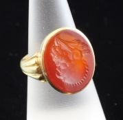 A George V 18ct gold and carnelian intaglio ring, with fluted shoulders and carved with the head of