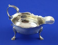 A George III silver sauceboat, with flying scroll handle and cut rim, on three hoof feet, NS & AN,