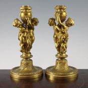 A pair of 19th century French ormolu figural candlesticks, each modelled as two cherubs supporting