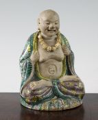 A Chinese famille verte glazed biscuit seated figure of Luohan, 18th century, wearing brocade