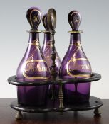 A three bottle decanter and stand, c.1810, the amethyst glass bottles gilt decorated with faux wine